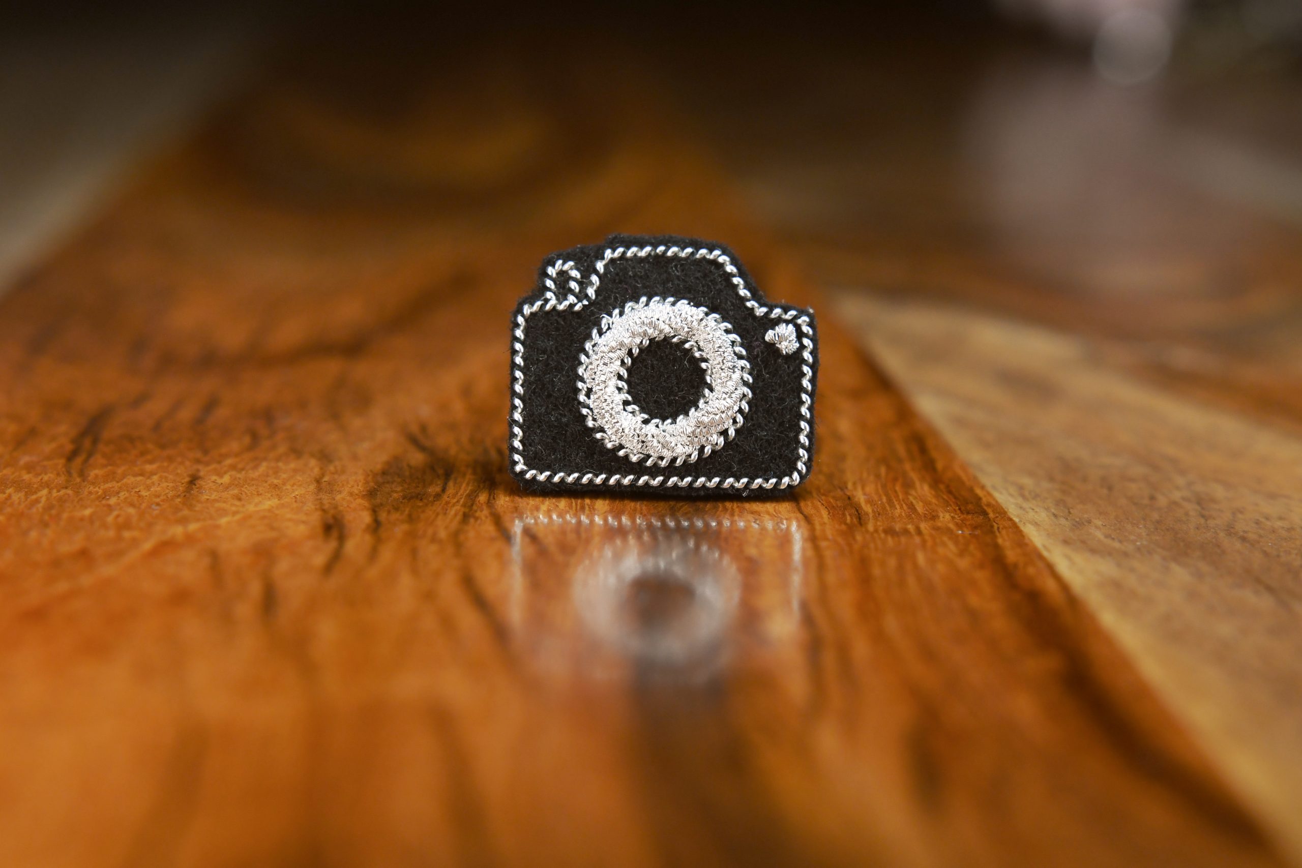 Pin's appareil photo (argent, fond noir).